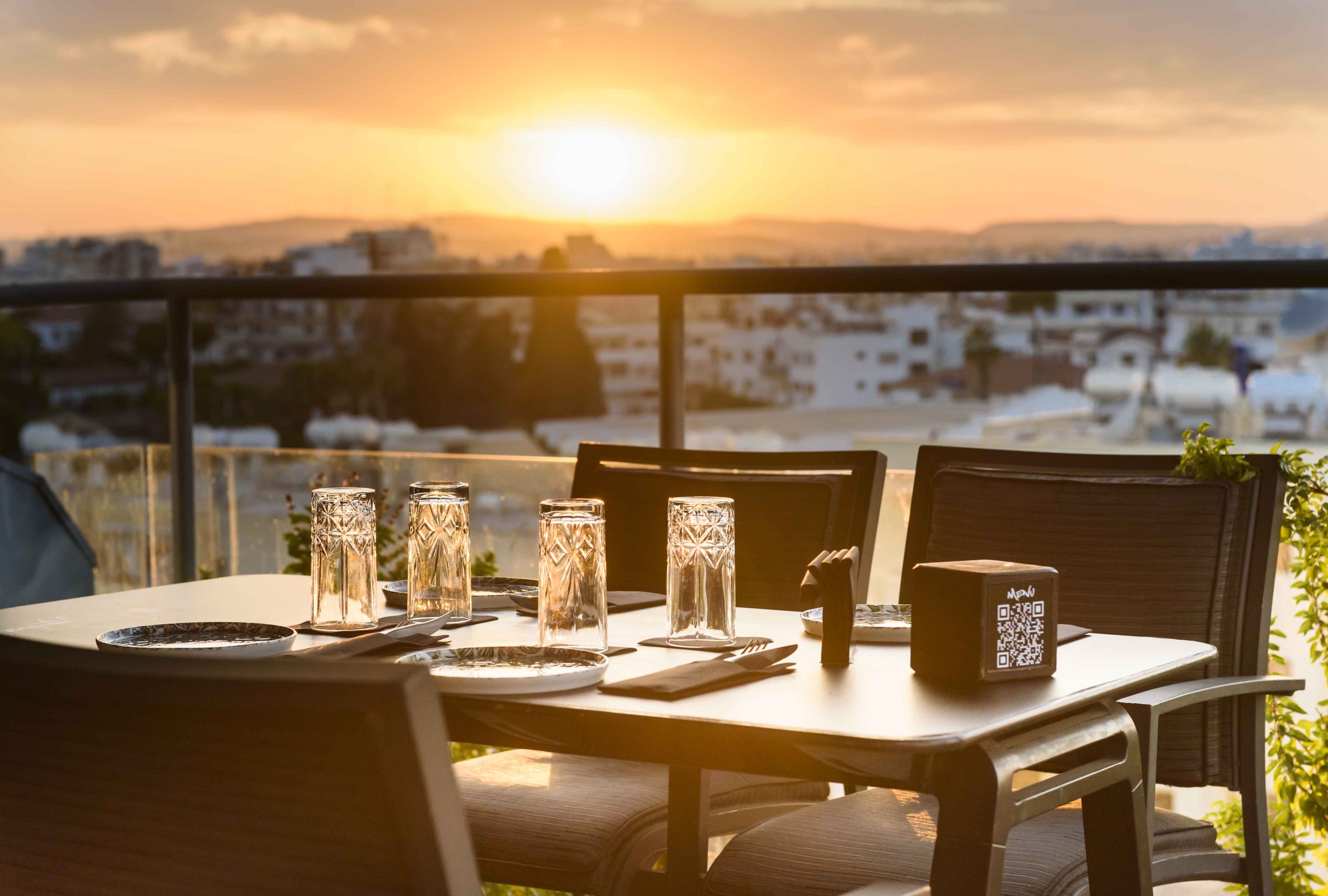 Table set for dinner with glasses reflecting the sunset at Memories Rooftop