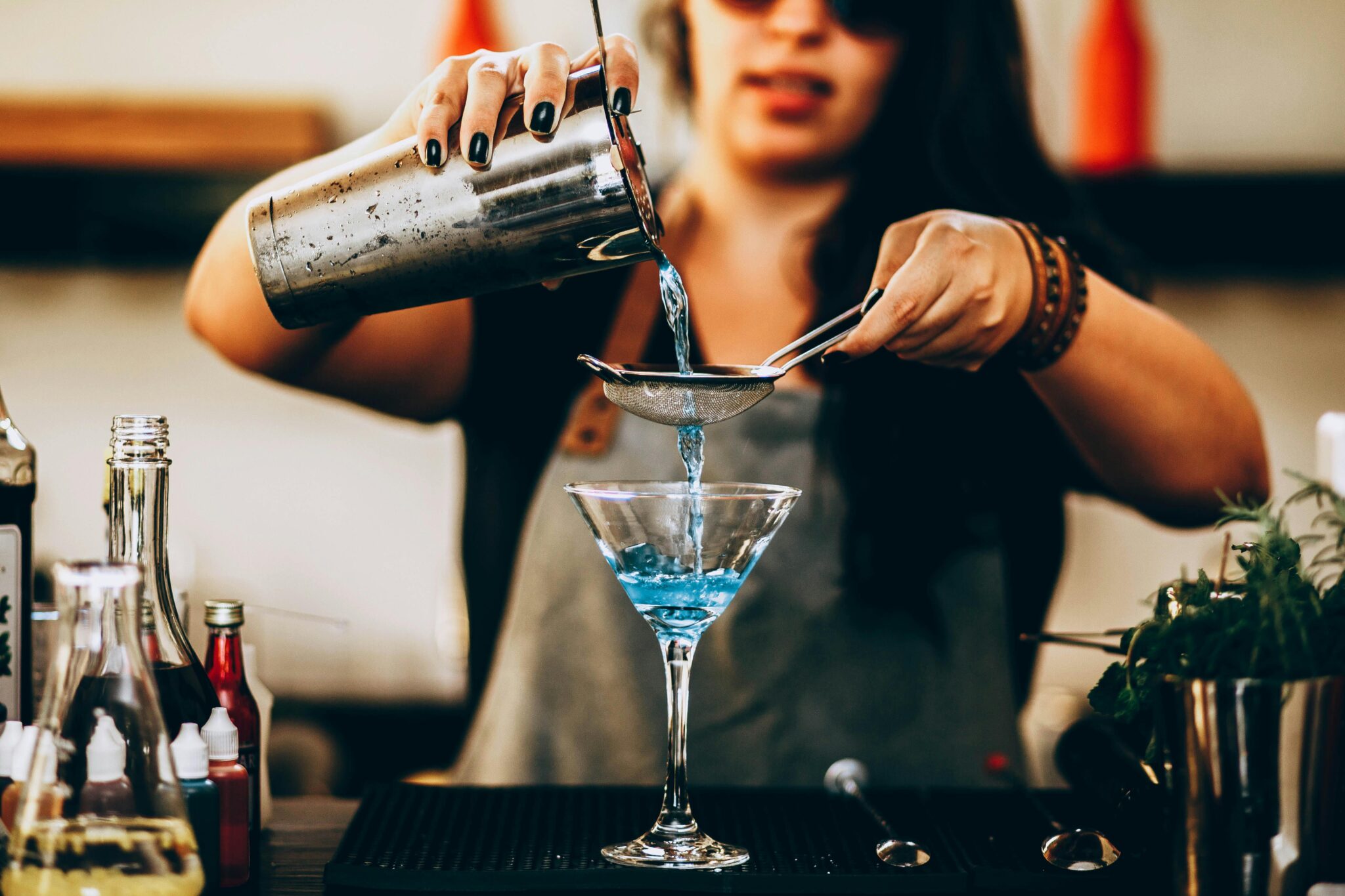 Bartender preparing a blue cocktail at a rooftop bar