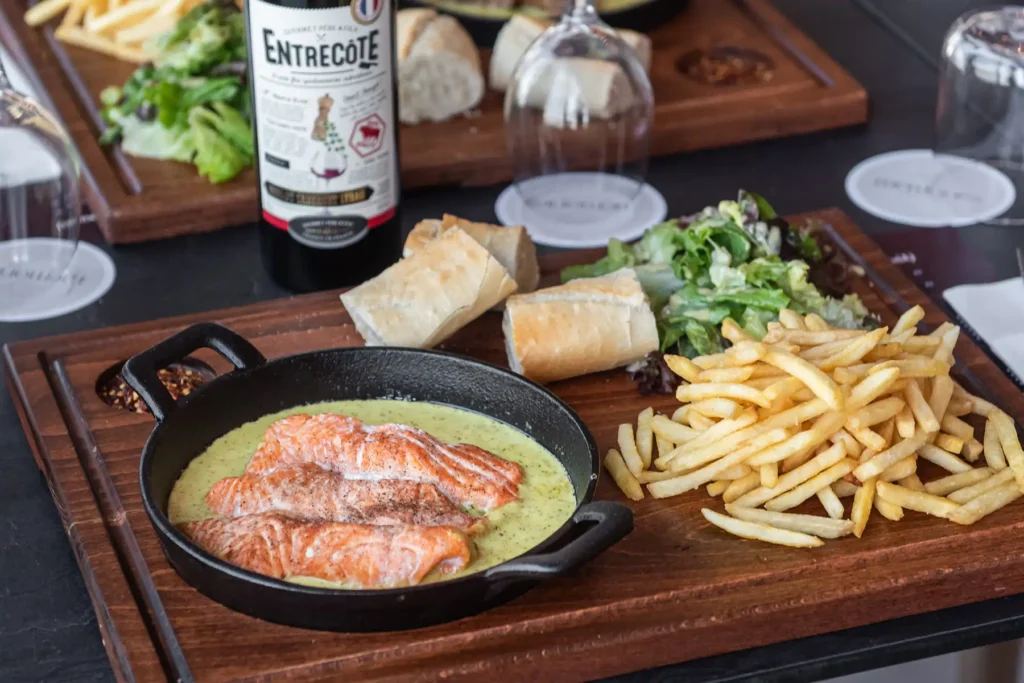 Salmon filet in creamy entrecôte sauce with fries, salad and baguette at rooftop restaurant Larnaca