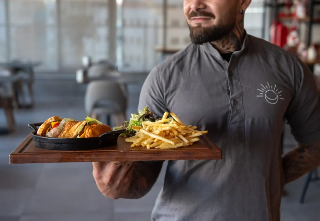 Staff presenting a board with burger, fries and salad at rooftop restaurant in Larnaca