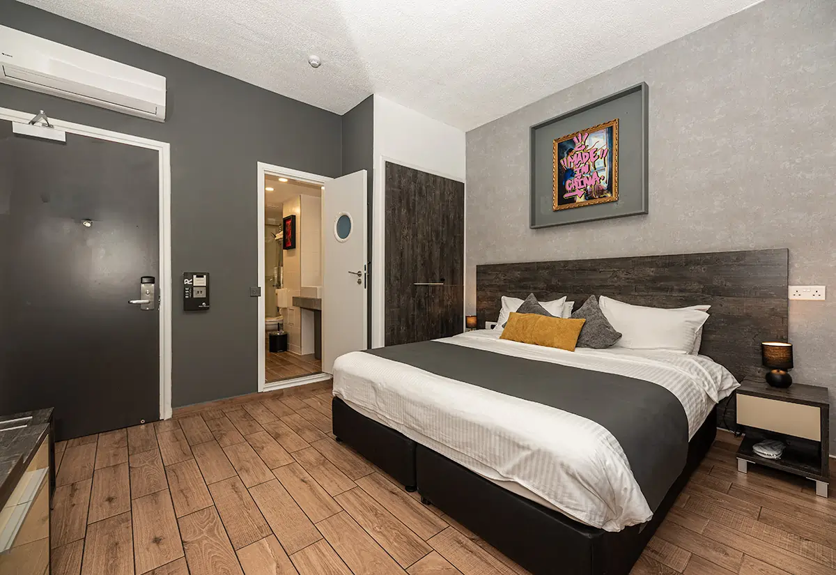 Modern boutique hotel room in Larnaca with double bed, ensuite bathroom, wooden floor and urban art decor