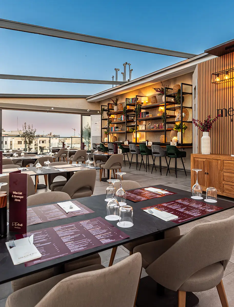 Rooftop restaurant terrace at sunset with modern tables, comfortable seating, and panoramic urban views