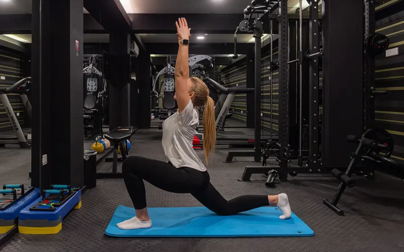 Woman stretching on yoga mat in the fitness center at Rise Urban Art Hotel