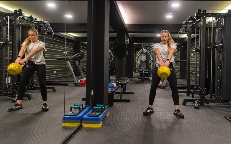 Woman performing kettlebell swing exercise in the Rise Urban Art Hotel fitness center in Larnaca