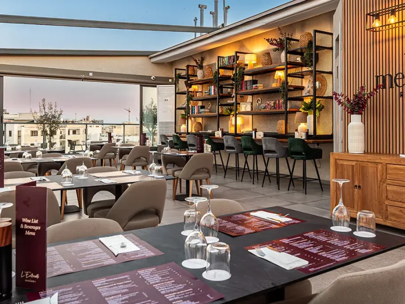 Rooftop restaurant terrace at sunset with modern tables, comfortable seating, and panoramic urban views