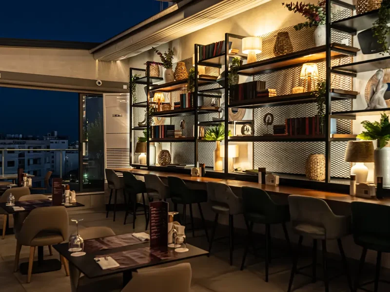 Contemporary rooftop restaurant interior with decorative shelving, modern seating, and ambient lighting in Larnaca